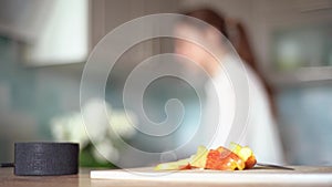 Cooking with the functions of a smart home. A young woman uses a voice assistant in her kitchen closeup