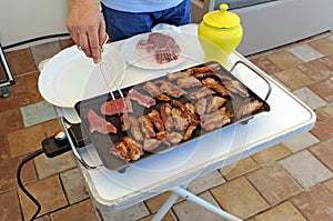 Cooking grilled Iberian pork (spanish lagartitos) on an electric grill.