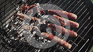 Cooking grilling bacon and sausages on bbq grid outdoors for friends picnic party