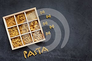 Cooking, healthy food concept. Different types of pasta in a wooden box on a dark background. View from above