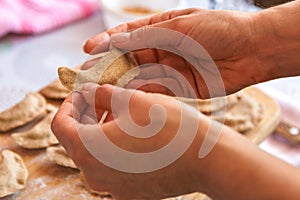 Cooking healthy food at home. closeup woman hands preparing dumplings from rye flour over wooden cutting board