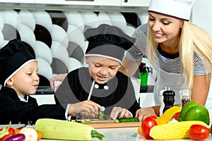 A family of cooks.Healthy eating. Happy family mother and children prepares vegetable salad in kitchen