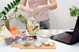 Cooking at home a woman watches online video recipes on a laptop and cooks in the kitchen at home Pickled pink cabbage