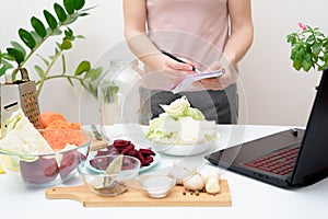Cooking at home a woman watches online video recipes on a laptop and cooks in the kitchen at home Pickled pink cabbage