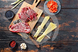 Cooking ingredients for Stir fry noodles with vegetables and beef . Machete steak and noodles on wooden background. Space for text