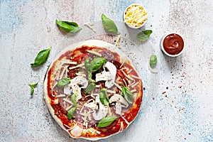 Cooking Italian pizza with tomato sauce, fresh tomatoes, cheese, mushrooms, salami slices and basil .