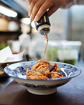 Cooking karaage chicken, japanese fried chicken in a traditional blue bowl with sauce, upright