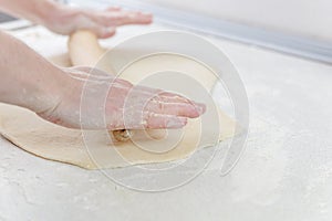 Cooking in the kitchen baking. Female hands are holding rolling pin sprinkled with flour.