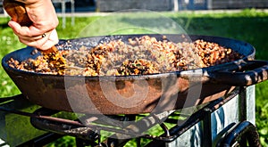 Cooking and making traditional Spanish Paella in iron cast pan.