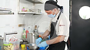 Cooking. man chef, in protective gloves and a mask, prepares food in kitchen, in canteen. health food and safety concept