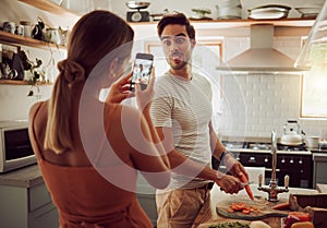 Cooking man sticking out tongue to make silly, goofy and funny face to pose for a photo while making food in the kitchen