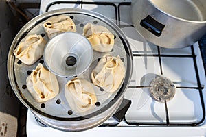 Cooking of Manti dumpling in metal steamer pot