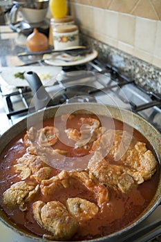 Cooking marrowbone in pan with tomato sauce