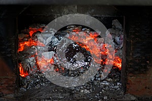 Cooking meal on the live coals in in the Russian stove. Rustic authentic food. Baked food in foi.