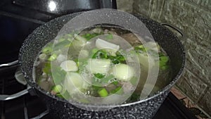 Cooking meat broth with herbs in a saucepan
