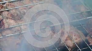 Cooking meat on a grill over smoke and coals.