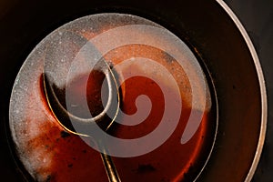 Cooking a morel sauce of beef stock and port wine in a pot with spoon, dark background, copy space, high angle view from above