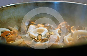 Cooking mussels, prawns and crabs on a pan. Close-up view of sea food in a frying pan. Tranditional cooking