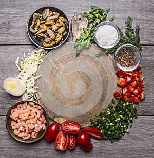 Cooking mussels shrimp tomatoes onions parsley dill garlic seasoning salt on a cutting board frame wooden background top view c