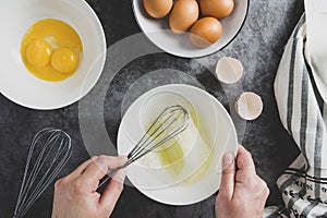 Cooking omlette. Woman's hands cookingomlette, breaking an fresh egg. Dark background. Food flat lay