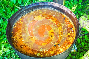 Cooking outdoors. Solyanka, meat hodgepodge soup in a large pot photo