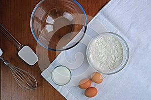 Cooking pancakes on wooden background top view. Ingredients for making dough. Eggs, flour, milk