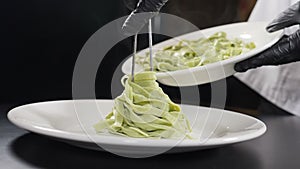 Cooking pasta in Italian restaurant. Chef serving cooked pasta on plate. Slow motion. Vapour or White steam rising up on