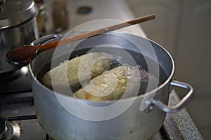 Cooking phase of dumplings in the boiling water set in aged silver aluminum pot on the gas cooker