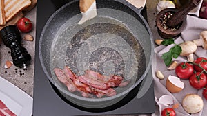 cooking Pieces of flavorful sliced organic bacon fried in a pan