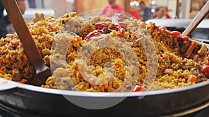 Cooking pilaf in a cauldron. Rice with meat and vegetables. Asian traditional dish - pilaf. National tasty food. Close