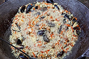 Cooking pilaf with mussels dish in a cauldron, outdoor