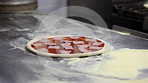 Cooking pizza in a restaurant, cook puts pizza ingredients