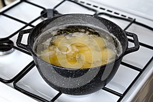 Cooking potato in a pot with boiling water on a gas stove