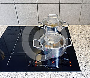 Cooking pots on a modern black glass-ceramic cooktop