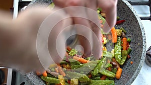 Cooking process, healthy food, vegetarian cuisine. Steaming vegetables frying on a pan being mixed a spatula. Dinner are