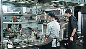 Cooking process. Professional team of chef and two young assistant preparing food in a restaurant kitchen