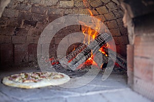 Cooking real pizza in a brick oven. Wood and fire are burning