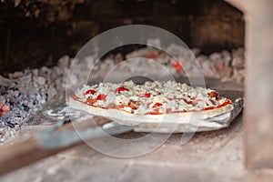 Cooking real pizza in a brick oven. Wood and fire are burning