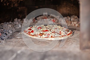 Cooking real pizza in a brick oven. Wood and fire are burning