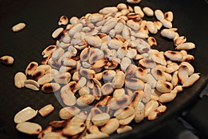 Cooking roasted ground peanuts on pan. Selective focus
