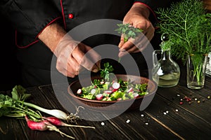 Cooking a salad of fresh vegetables by the hands of a chef in the kitchen. Vegetarian cuisine. Recipe menu for hotel