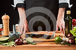 Cooking salmon steaks. Chef standing near the desk with various ingredients