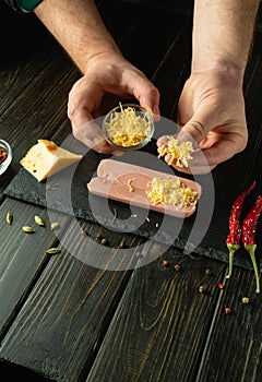 Cooking sausages on the kitchen table by the hands of a cook. Adding cheese to cut raw sausage meat before grilling. Tasty snack