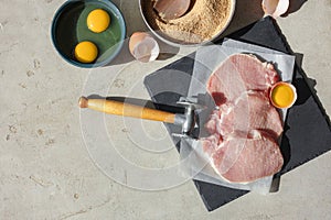 Cooking schnitzel. Raw pork chops, meat mallet and ingredients on grey table, flat lay with space for text