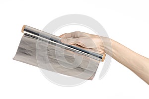 Cooking and shisha topic: human hand holding a foil isolated on white background in studio