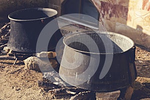 Cooking in sooty old cauldron on campfire at sunny day.