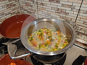 Cooking soup in a metal pan on a gas stove, chicken vegetable soup