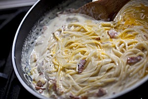 Cooking spaghetti carbonara in pan.