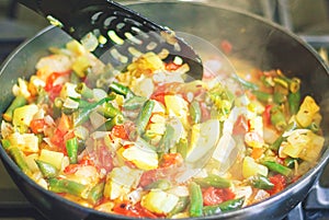 Cooking stewed vegetables in a deep pan, vegetarian food. Stew of zucchini, tomatoes, onions, paprika and string beans.Close-up