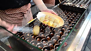 Cooking takoyaki is a ball-shaped Japanese snack at DÅtonbori in Osaka, Japan